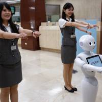 SoftBank\'s humanoid robot Pepper performs with employees at First Bank branch in Taipei on Thursday. | REUTERS