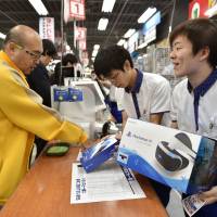 A customer buys a Sony PlayStation VR headset at an electronics store in Tokyo on Thursday. | AFP-JIJI