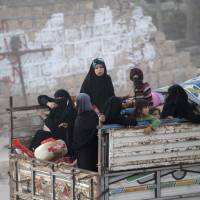 People who fled Islamic State-contolled areas travel on the back of a vehicle in al-Rai town, northern Aleppo countryside, Syria, Tuesday. | REUTERS