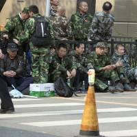 Protesters wearing green fatigues gather outside the Ministry of National Defense headquarters in Beijing on Oct. 11. China veterans' protests for better pensions regarded as a test for nation's leaders