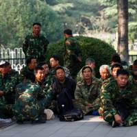 Uniformed people take part in a protest outside the Bayi Building, a major military building in Beijing, on Tuesday. | REUTERS
