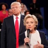 Republican U.S. presidential nominee Donald Trump listens as Democratic nominee Hillary Clinton answers a question from the audience during their town hall debate at Washington University in St. Louis on Sunday. | REUTERS