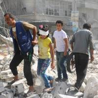 Syrians walk over rubble following airstrikes on the rebel-held Fardous neighborhood of the northern embattled Syrian city of Aleppo on Wednesday. | AFP-JIJI
