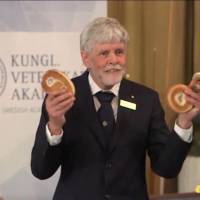 A screenshot of a live broadcast of the Nobel Prize announcement in which Thors Hans Hansson, a member of the Nobel committee for physics, explains concepts of topology using a cinnamon bun, a bagel and a pretzel. | SOURCE: NOBELPRIZE.ORG / FACEBOOK