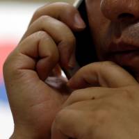 A North Korean defector talks on the phone during an interview in Seoul on Sept. 26. He requested that his face and name be withheld. | REUTERS