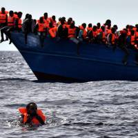 Migrants wait to be rescued as they drift in the Mediterranean some 20 nautical miles north off the coast of Libya on Monday. Italy coordinated the rescue of more than 5,600 migrants off Libya, three years to the day after 366 people died in a sinking that first alerted the world to the Mediterranean migrant crisis. | AFP-JIJI