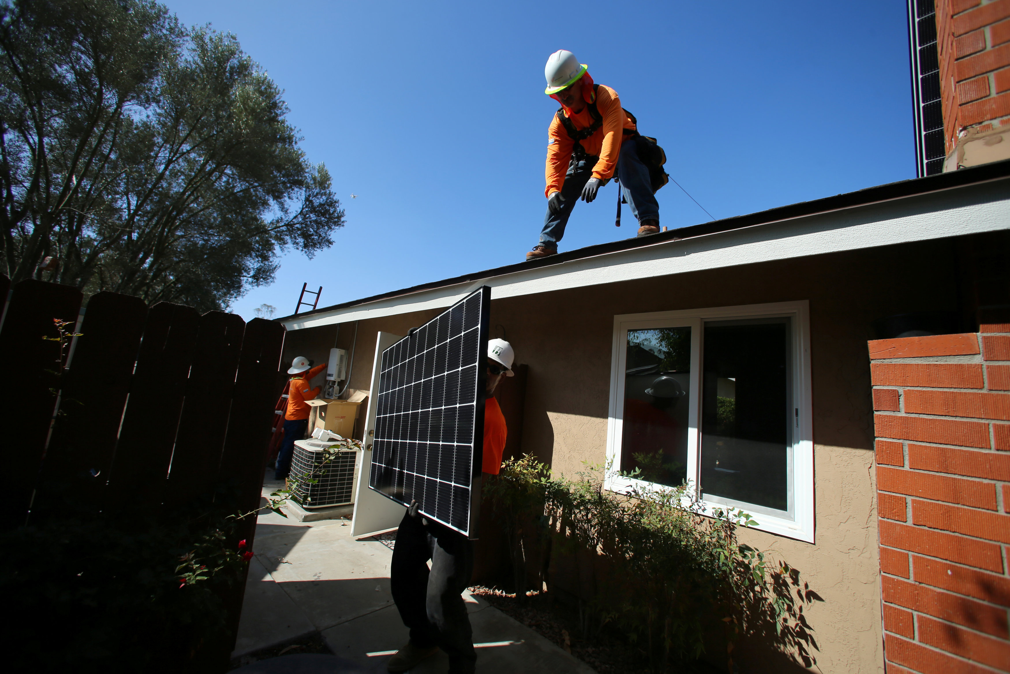 Workers install solar panels on the roof of a home in Scripps Ranch, northeastern San Diego, on Oct. 14. | REUTERS