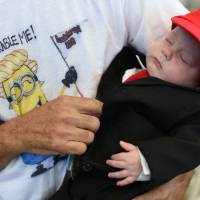 Three-month old Matthew Cohen is dressed in a Donald Trump-style suit by his father, Les Cohen, of Victorville, California, before the start of Republican presidential candidate Donald Trump\'s rally on Wednesday at the Henderson Pavilion in Henderson, Nevada. | AFP-JIJI