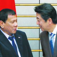 Philippine President Rodrigo Duterte is greeted by Prime Minister Shinzo Abe at the start of their meeting in Tokyo on Wednesday. | POOL / VIA AFP-JIJI