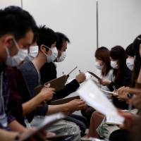 Participants wearing surgical masks converse during a masked match-making event held in Tokyo on Sunday. | REUTERS