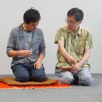 Rakugo teacher Tatsuya Sudo instructs a student on how to make use of props when conveying a story to the audience at his English rakugo class in Tokyo last month. | MAGDALENA OSUMI