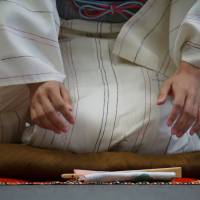 A rakugo apprentice sits on stage with a traditional tenugui cloth and sensu fan  during a rehearsal in Tokyo\'s Adachi Ward last month. | MAGDALENA OSUMI