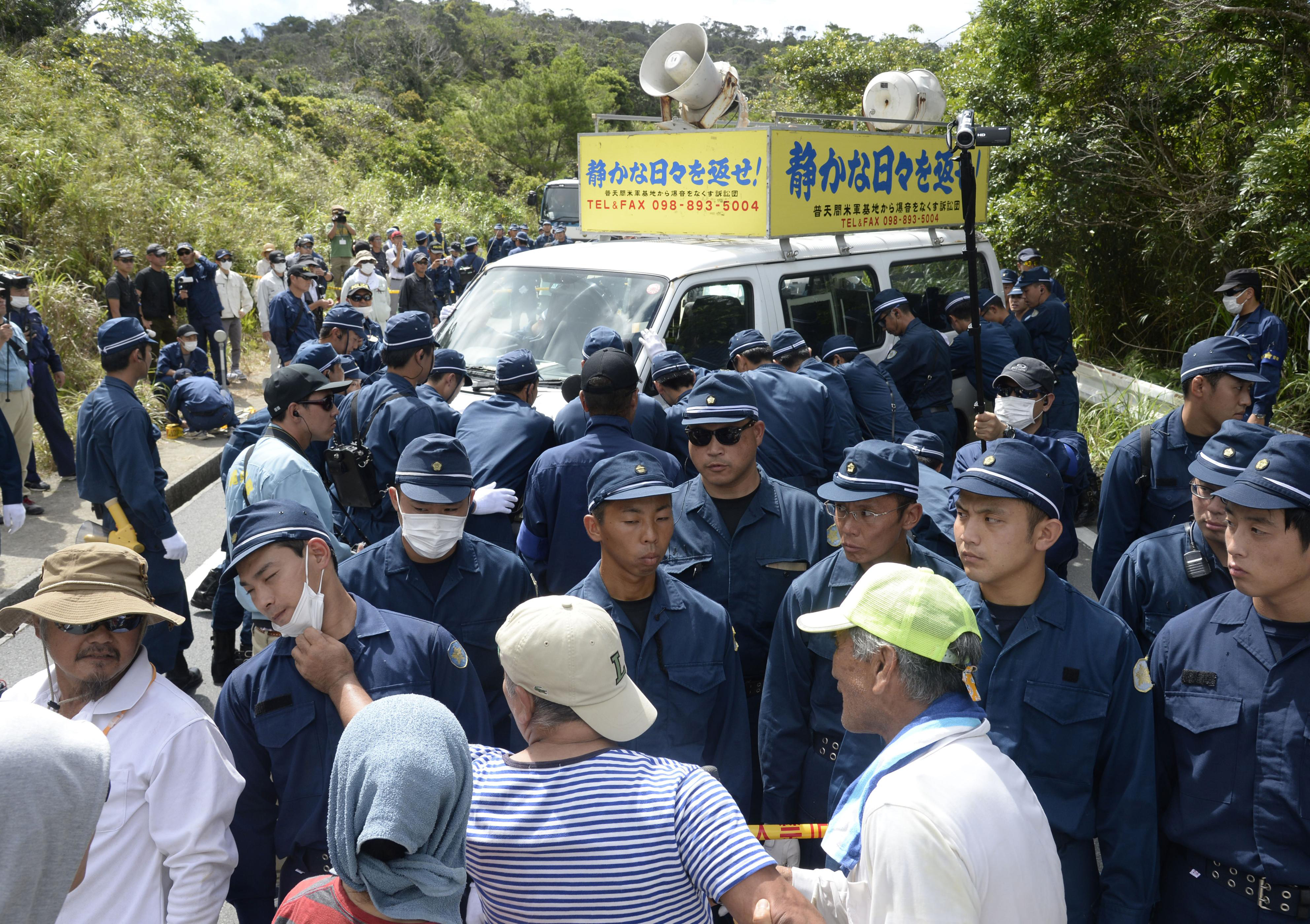 Local residents protest as police try to remove a minivan placed by protesters in the middle of a road near a U.S. military training site in Takae, Okinawa Prefecture, on Sept. 15. | KYODO