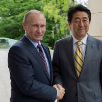 Russian President Vladimir Putin shakes hands with Prime Minister Shinzo Abe during a meeting in May at the Bocharov Ruchei state residence in Sochi, Russia. | REUTERS
