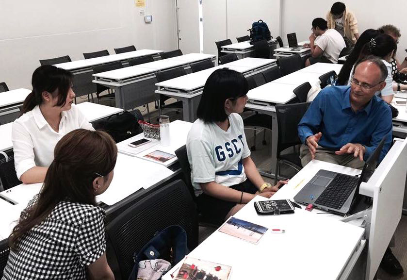 Freelance journalist Laird Harrison, who also serves as director of the Institute for Education in International Media, works with students at the Kindai University during a visit to Kyoto in June. | COURTESY OF RACHELE KANIGEL