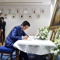 Prime Minister Shinzo Abe signs a condolence book for late King Bhumibol Adulyadej at the Thai Embassy in Tokyo on Friday. | AFP-JIJI
