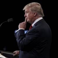 Donald Trump listens to rival Hillary Clinton during their presidential debate in Las Vegas on Wednesday. | REUTERS