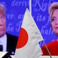 Extremely loud and incredibly close: A Japanese flag stands in front of a monitor showing the first U.S. presidential debate between Republican nominee Donald Trump and his Democratic rival, Hillary Clinton, at a foreign exchange trading company in Tokyo last Tuesday. | REUTERS