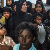 Waiting in vain: Rohingya women and children stand in a shelter in Indonesia’s Aceh province after fleeing persecution in Myanmar in May 2015. | AFP-JIJI