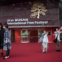The BIFF fans: Visitors take selfies outside the entrance to the 21st Interational Film Festival, showing their support for the event, which has been beset by controversy over the past two years. | AFP-JIJI