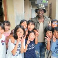 Expanding horizons: Abdou Baye Fall poses with schoolchildren in Fukushima during a visit to the city last month. | COURTESY OF ABDOU BAYE FALL