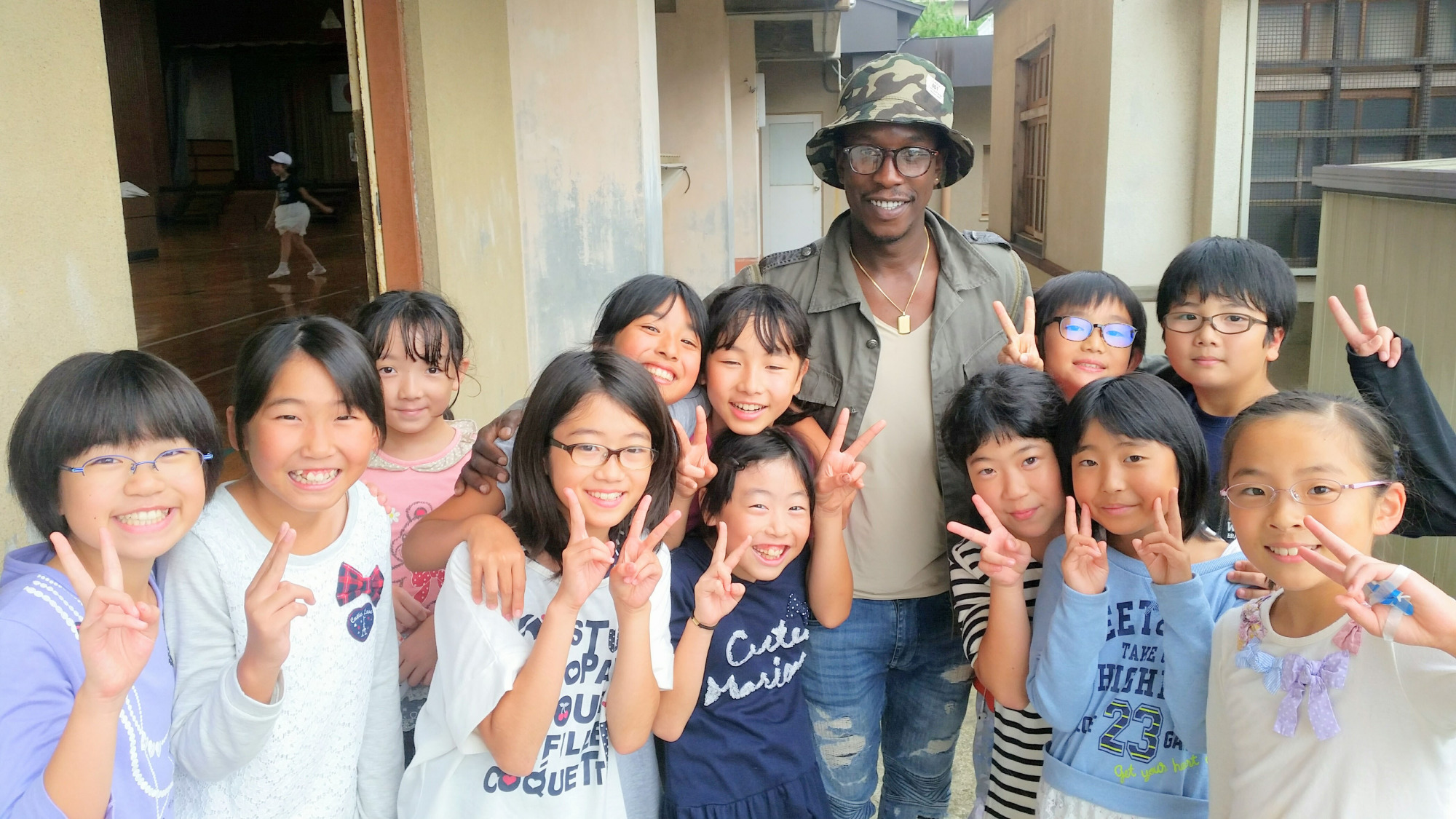 Expanding horizons: Abdou Baye Fall poses with schoolchildren in Fukushima during a visit to the city last month. | COURTESY OF ABDOU BAYE FALL