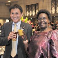 Uganda\'s Ambassador Betty Grace Akech-Okullo (right) shares a toast with Parliamentary Vice Minister for Foreign Affairs and House of Representatives member Shunsuke Takei at a reception to celebrate the country\'s 54th anniversary of independence at the Hotel Okura, Tokyo, on Oct. 9. | YOSHIAKI MIURA