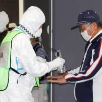 A man is screened for radioactive contamination during an evacuation drill in Itoshima, Fukuoka Prefecture, on Monday. About 2,500 residents of Saga, Fukuoka and Nagasaki prefectures took part in the exercise, which tested responses to a serious accident at Kyushu Electric Power Co.\'s Genkai nuclear plant in Saga Prefecture. | KYODO