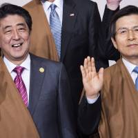 Prime Minister Shinzo Abe (left) and South Korea\'s Prime Minister Hwang Kyo-ahn wave as they take part in the traditional \"family photo\" on the final day of the Asia-Pacific Economic Cooperation (APEC) Summit at the Lima Convention Centre in Lima on Sunday. Asia-Pacific leaders were expected to send a strong message in defense of free trade as they wrap up a summit that has been overshadowed by U.S. President-elect Donald Trump\'s protectionism. | AFP-JIJI