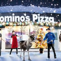 In this image photo uploaded on the official Facebook page of Domino\'s Pizza Japan, employees of the major pizza chain send out a reindeer with a pizza box strapped around its back to a customer. | AFP-JIJI