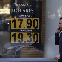 People stand outside an exchange house advertising the sale of dollars at the rate of 19.30 Mexican pesos per dollar in Mexico City Nov. 1. | AP