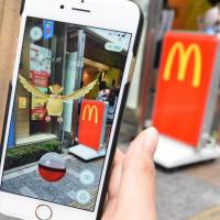A woman plays \"Pokemon Go” game on her smartphone in front of a McDonald\'s restaurant in Tokyo\'s Akihabara shopping district.  | AFP-JIJI