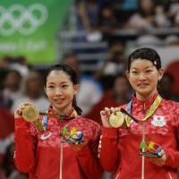 Japan\'s Misaki Matsutomo (left) and Ayaka Takahashi react after receiving the gold medal in women\'s doubles badminton at the 2016 Summer Olympics in Rio de Janeiro. | AP
