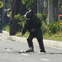 A police bomb squad member prepares to carry out a controlled detonation near a suspicious package found near the U.S. Embassy in Manila on Monday. | AFP-JIJI