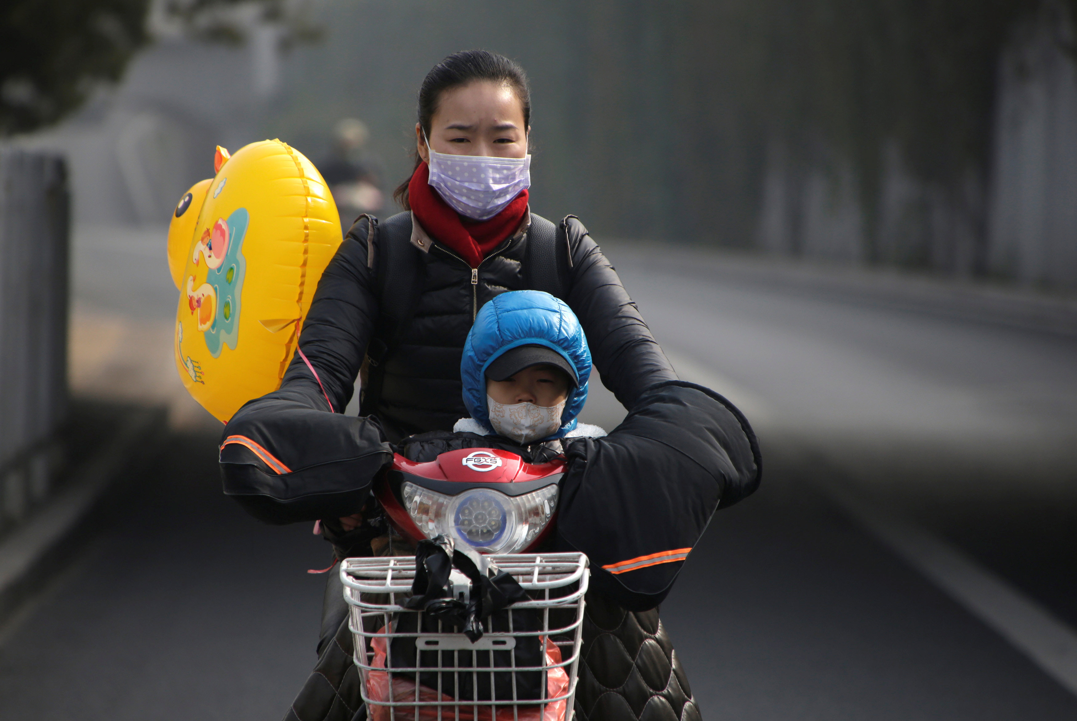 A woman and her son wearing masks ride an electric bicycle on a hazy day in Beijing on Nov. 4. The election of climate change skeptic Donald Trump as U.S. president may force China to take the lead in fight against global warming. | REUTERS