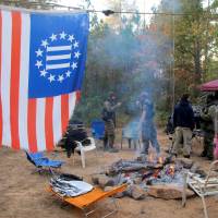 As the camp fire burns, members of the Three Percent Security Force militia gather for a field training exercise in Jackson, Georgia, on Oct. 29. | REUTERS