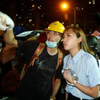Pro-independence legislator-elect Yau Wai-ching (right) talks with a protester during a confrontation with the police outside the China Liaison Office in Hong Kong on Sunday. | REUTERS