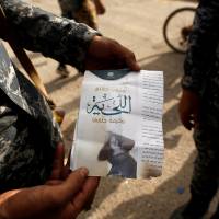 An Iraqi soldier shows a pamphlet that reads \"Wearing beards is compulsory, shaving is prohibited\" along a street in the town of Shura, which was recaptured from the Islamic State group, on Saturday. | REUTERS