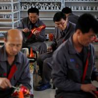 North Korean workers make soccer shoes inside a temporary factory at a rural village on the edge of Dandong, China, in October 2012. | REUTERS