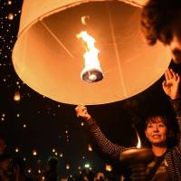 People hold on to paper lanterns to mark the annual Yi Peng festival in the popular tourist city of Chiang Mai in northern Thailand on Nov. 14. | AFP-JIJI