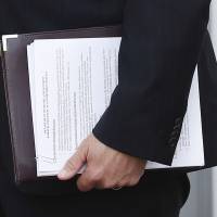 Kansas Secretary of State Kris Kobach holds a stack of papers as he prepares to meet with President-elect Donald Trump at the Trump National Golf Club Bedminster clubhouse Sunday in Bedminster, New Jersey. Kobach, a immigration adviser to rump and a possible candidate for a top government post, wants to make some changes at the Homeland Security Department, including reinstituting a registration system for certain immigrants. | AP