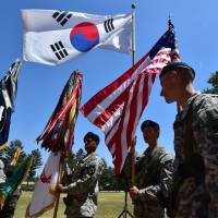 American soldiers hold the South Korean and U.S. flags before a joint ceremony at a U.S. Army base in Uijeongbu, just north of Seoul, in June 2015. | AFP-JIJI
