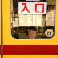 A boy peeks out from the window of a streetcar on Oct. 20. | SATOKO KAWASAKI