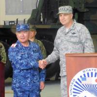 Lt. Gen. Jerry Martinez, commander of U.S. forces in Japan, shakes hands with Katsutoshi Kawano, chief of the Self-Defense Forces\' Joint Staff, after a joint news conference at the U.S. military base in Iwakuni, Yamaguchi Prefecture, on Thursday. | KYODO