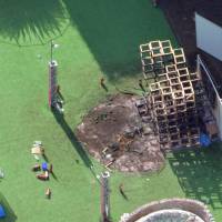 Police officers investigate the remains of the jungle gym installation that caught fire Sunday at an event held in the Meiji Jingu Gaien area of Tokyo. A 5-year-old boy died in the inferno. Incandescent bulb likely started fire that killed boy at Tokyo design event