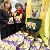 Costumed fans hold copies of the Japanese translation of J.K. Rowling\'s \"Harry Potter and the Cursed Child,\" at a bookstore in Hachioji, Tokyo, early Friday right after the eighth tale in the fantasy series was released. | KYODO