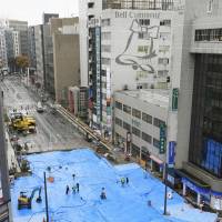 Tarps protect the work site at a huge sinkhole in the city of Fukuoka to protect it from rain Monday. | KYODO
