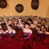 Wine soak: Guests toast with the 2016 Beaujolais Nouveau wine at the Hakone Yunessun spa resort. | AFP-JIJI