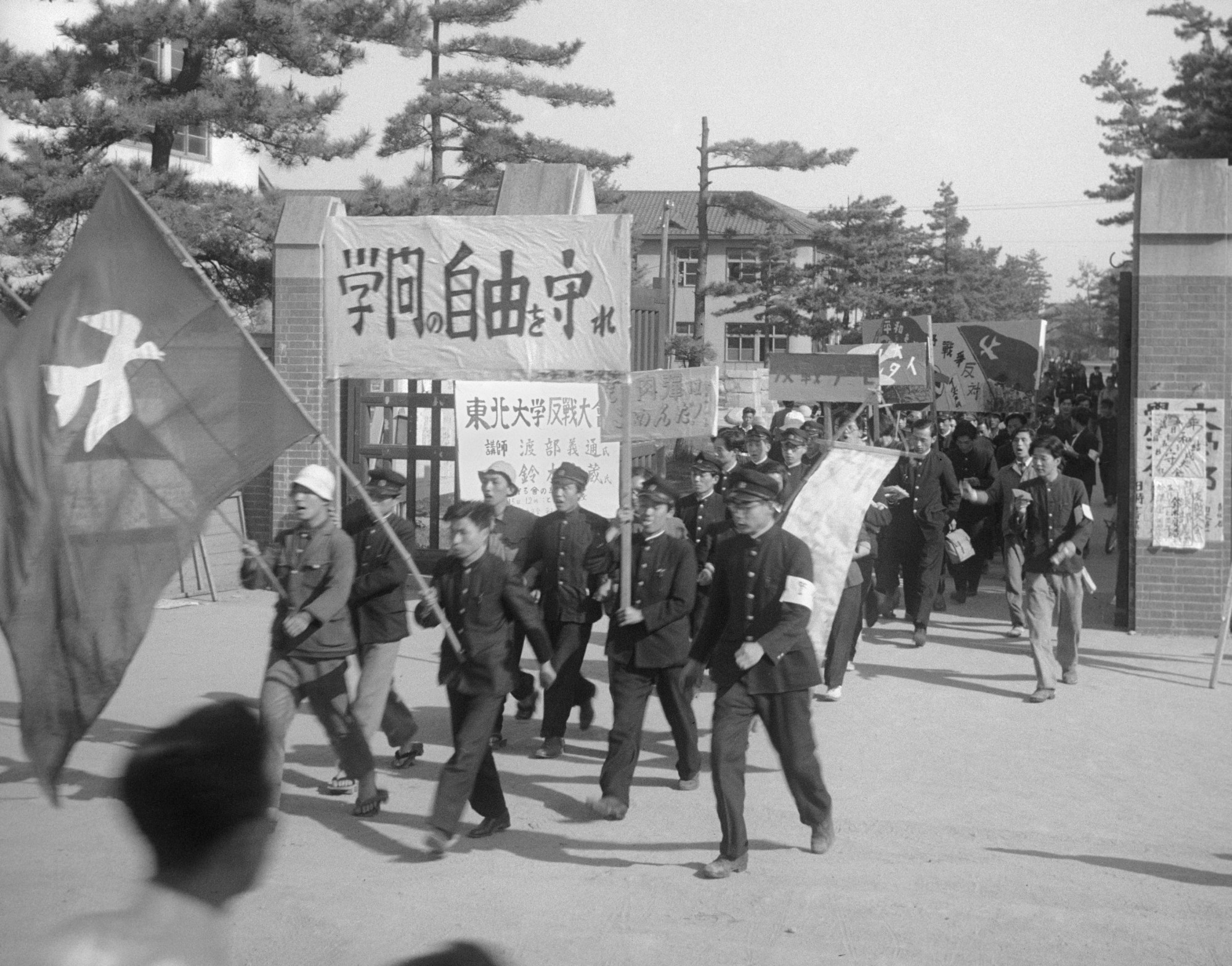 Venerable site: Students taking part in an anti-war rally file out through the gates of Tohoku University in Sendai in 1950. The storied university recently revealed that it plans not to renew the fixed-term contracts of up to 3,200 employees, thereby ensuring that they will not be able to become regular staff according to a recent revision to the Labor Contract Law. | KYODO