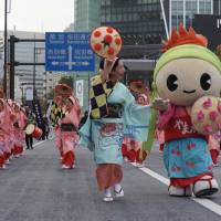 A lead performer of Yamagata Hanagasa guides the mascot Hangata Beni-chan, who wears a costume touting the prefecture\'s famous cherries. | MARK THOMPSON